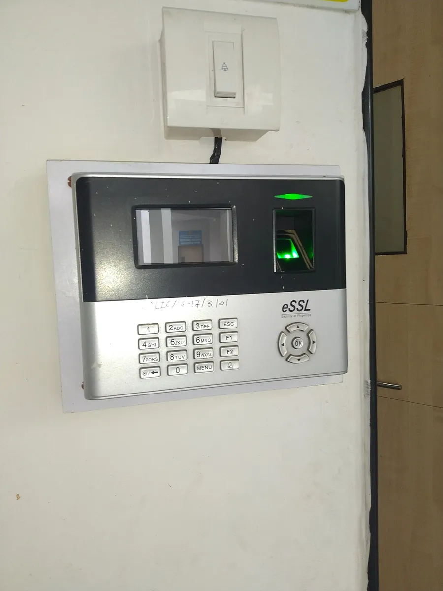 Lector biométrico de huella digital montado en una pared, con sensor iluminado