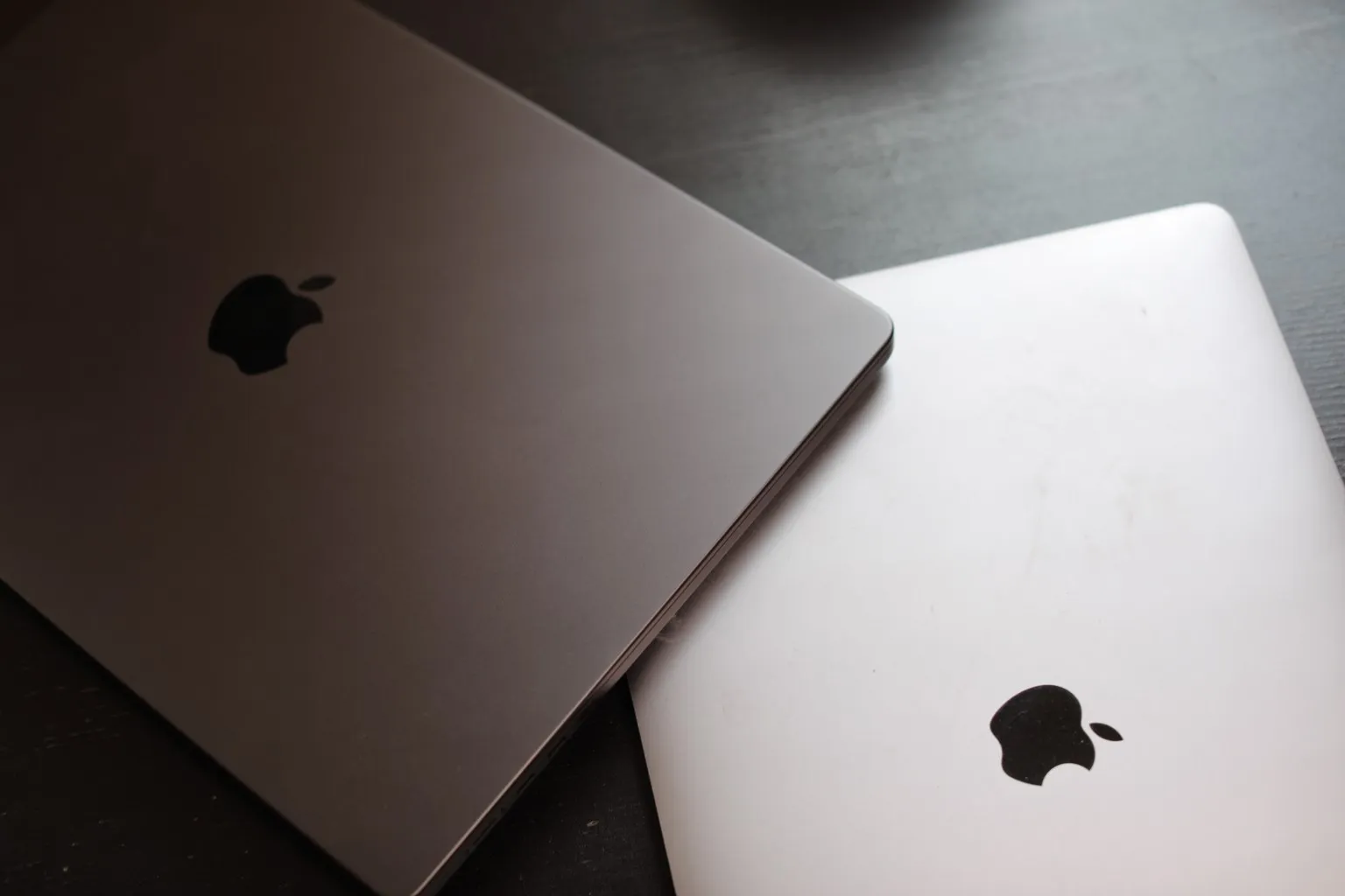 Dos MacBook cerradas, con el logo de Apple, sobre una mesa oscura